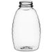 A clear plastic Classic Queenline honey bottle with a lid on a white background.