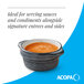 A small midnight blue matte stoneware sauce cup filled with sauce.
