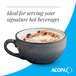 A matte midnight blue stoneware cup with a handle, filled with a hot beverage and topped with whipped cream and chocolate pieces.
