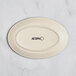 A white oval Acopa stoneware platter with black text on it.