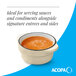 A small cream white matte stoneware sauce cup filled with sauce.