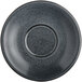 A black Acopa stoneware saucer with a speckled rim and small dots in the center.