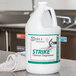 A white jug of Noble Chemical Strike All Purpose Concentrated Cleaner with a green label on a counter.
