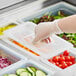 A hand in a glove using a Vigor translucent polypropylene lid to cover a plastic tray of vegetables.