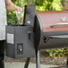 A person pouring wood pellets into a Backyard Pro wood-fire pellet grill.