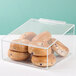 A clear plastic container with blueberry bagels inside on a bakery display counter.