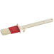 A white and red paint brush with a red plastic handle.