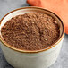 A bowl of ground brown powder with Regal Enchilada Seasoning.