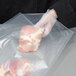 A person wearing a glove using an ARY VacMaster vacuum packaging bag to hold a piece of raw meat.