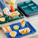 A right handed blue Choice compartment tray with food and a fork on it.