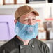 A man wearing a blue disposable beard net over his mouth.