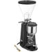 A silver and black Estella Caffe on-demand espresso grinder with a wooden spoon and metal container.