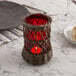 A Sterno red cylinder globe candle holder on a table.