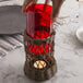 A person holding a red glass cylinder candle holder with a candle inside.