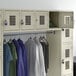 A beige Regency wall mount locker with several shirts hanging inside.