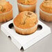 A group of muffins in a white Baker's Mark container.
