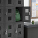 A Regency black 3 wide locker with a green backpack inside.