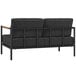A black loveseat with teak accents and metal bars.