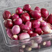 A clear plastic jar filled with peeled red pearl onions.