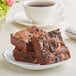 A Sweet Street Desserts chocolate chunk brownie on a plate with a cup of coffee.