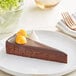 A slice of Sweet Street Desserts chocolate torte on a plate with oranges on top.