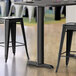 A black Lancaster Table & Seating stamped steel counter height table base.