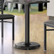 A Lancaster Table & Seating black table base with a round table and chairs in a restaurant dining area.