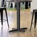 A black Lancaster Table & Seating 4" Counter Height Column Table Base on a table in a restaurant.