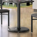 A Lancaster Table & Seating black round table base with two chairs.