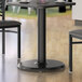 A Lancaster Table & Seating black metal standard height column table base with cups on it.