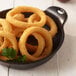 A plate of fried Golden Dipt onion rings on a white table.