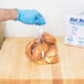 A person wearing blue gloves placing croissants in an Inteplast Group plastic bag.