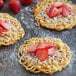 A group of three funnel cakes with strawberries and powdered sugar on a table.