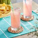 Two glasses of Jarritos Guava soda on a table with chips.