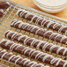 Chocolate covered pretzels made with Regal Foods white coating wafers on a cooling rack.