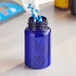 A blue 225cc PET packer bottle with white and blue pills being poured into it.