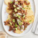 A plate of nachos topped with TenderBison ground bison, cheese, and avocado.