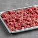 A metal tray filled with TenderBison steak tips.