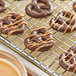 Chocolate covered pretzels cooling on a metal rack.