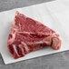 A piece of raw TenderBison T-Bone steak on a white surface.