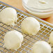 White dough balls on a metal rack.