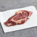A TenderBison raw ribeye steak on a white surface.