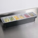 A Rubbermaid condiment bar with compartments filled with fruit.