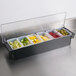 A black Rubbermaid condiment bar with cherries and olives in it.