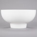 An American Metalcraft white porcelain footed bowl on a gray surface.
