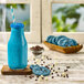 A blue drink in a bottle with a straw and a cookie.
