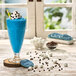 A blue drink topped with cookies and whipped cream.