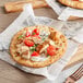 A Grecian Delight New York style white pita flatbread with chicken and vegetables on it.