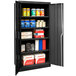 A black metal Hallowell storage cabinet with solid doors and shelves full of products.
