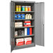 A gray metal Hallowell storage cabinet with shelves full of items.